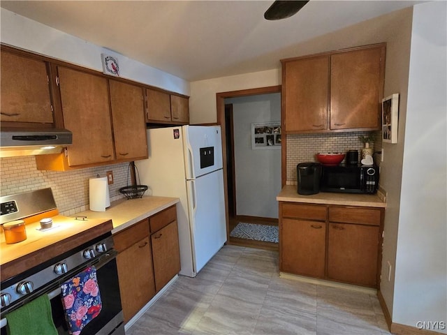 kitchen featuring stainless steel range, decorative backsplash, and white fridge