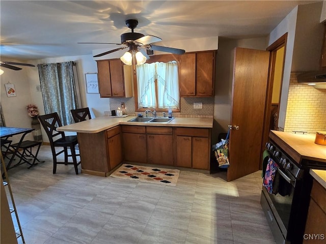 kitchen with kitchen peninsula, a breakfast bar area, backsplash, black stove, and sink