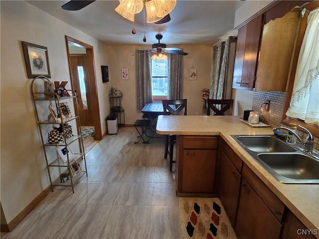 kitchen featuring decorative backsplash, sink, kitchen peninsula, and ceiling fan