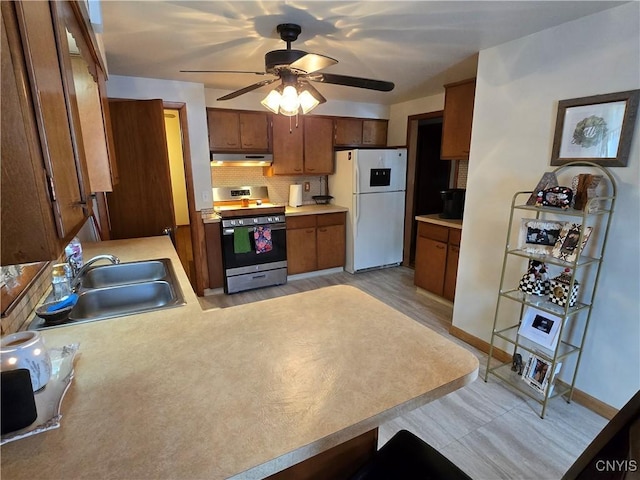 kitchen with stainless steel range oven, white refrigerator with ice dispenser, sink, kitchen peninsula, and ceiling fan