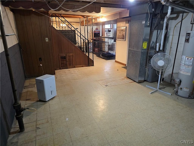 basement featuring heating unit, wood walls, and gas water heater