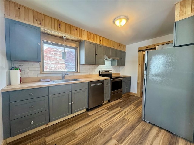 kitchen with gray cabinets, appliances with stainless steel finishes, tasteful backsplash, decorative light fixtures, and sink