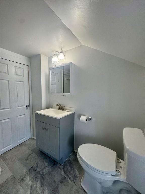 bathroom featuring vaulted ceiling, toilet, an inviting chandelier, and vanity