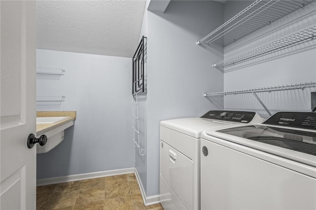 washroom with a textured ceiling and washer and clothes dryer