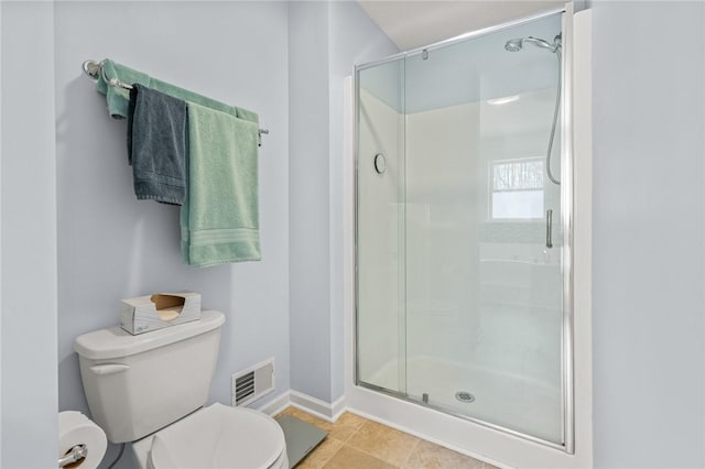 bathroom featuring toilet, tile patterned floors, and a shower with shower door