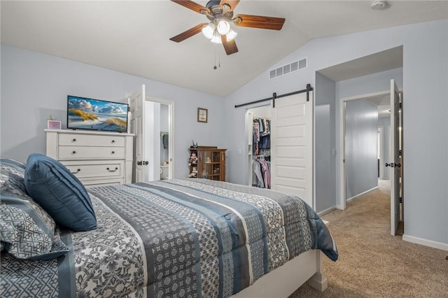 bedroom with lofted ceiling, a closet, ceiling fan, light colored carpet, and a barn door