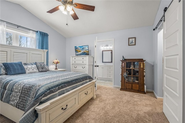 carpeted bedroom featuring ceiling fan, ensuite bath, a barn door, and vaulted ceiling