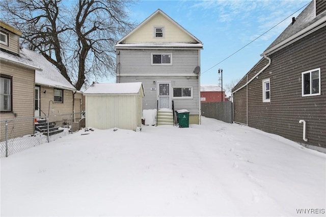 snow covered back of property with a storage unit