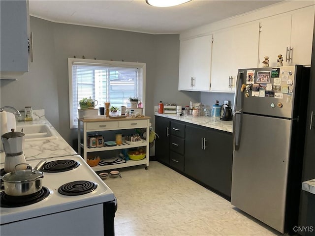 kitchen with sink, white cabinets, electric range, and stainless steel refrigerator