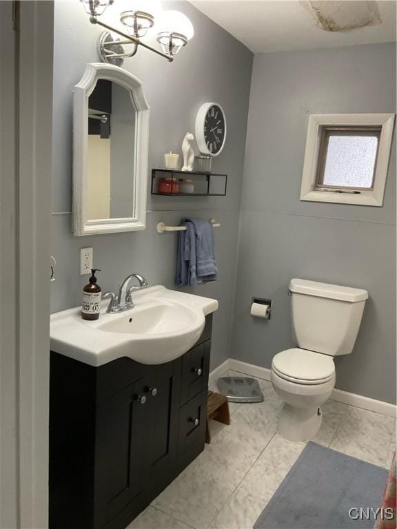 bathroom with toilet, vanity, a notable chandelier, and tile patterned flooring