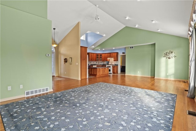 unfurnished living room featuring ceiling fan, wood-type flooring, and high vaulted ceiling