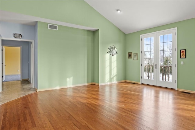 unfurnished room featuring lofted ceiling, light hardwood / wood-style floors, and french doors