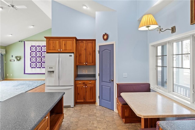 kitchen featuring ceiling fan, white fridge with ice dispenser, and high vaulted ceiling