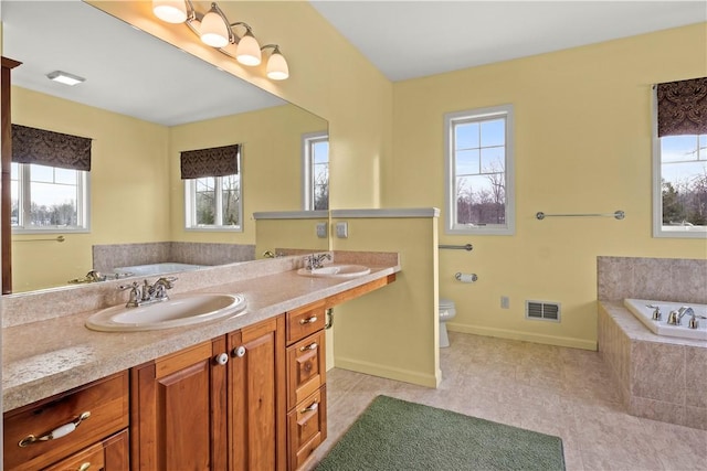 bathroom featuring toilet, tile patterned floors, tiled bath, and vanity