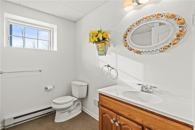 bathroom with toilet, vanity, baseboard heating, and a drop ceiling