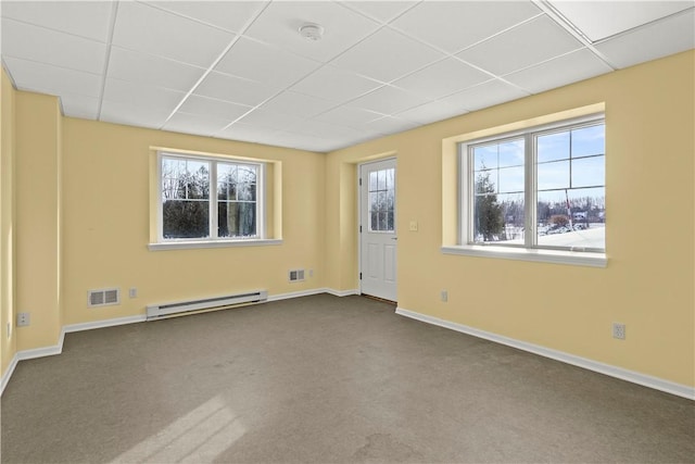 carpeted empty room featuring a paneled ceiling and baseboard heating