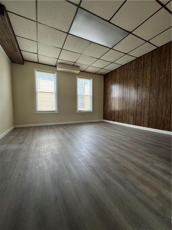 unfurnished room featuring hardwood / wood-style flooring, a paneled ceiling, and wood walls