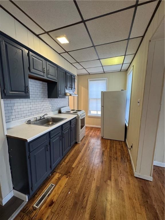 kitchen with sink, backsplash, dark hardwood / wood-style flooring, a drop ceiling, and white appliances