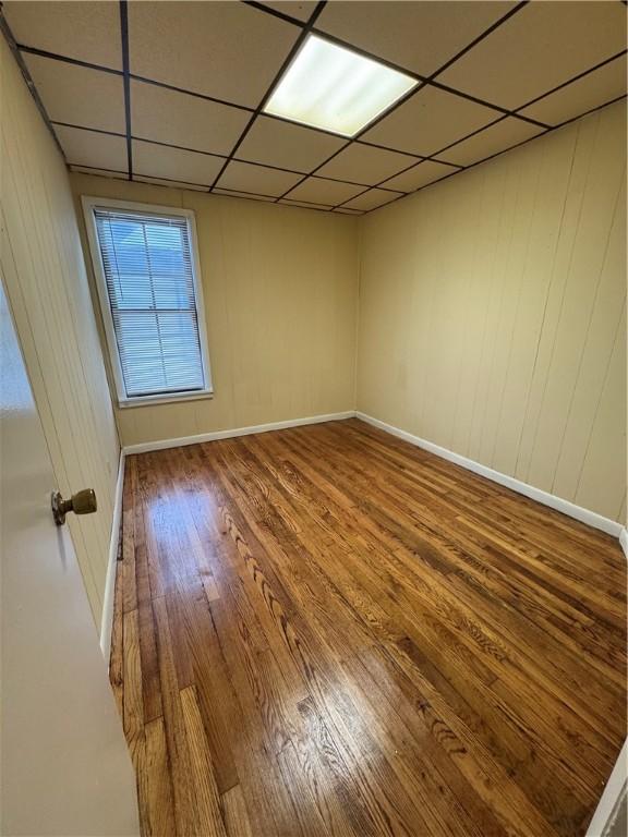 empty room featuring hardwood / wood-style flooring and a paneled ceiling