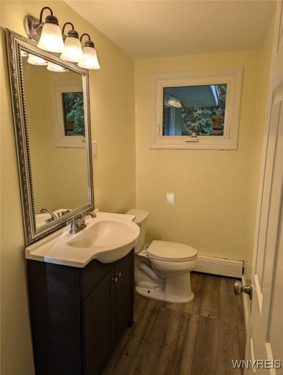 bathroom featuring hardwood / wood-style flooring, baseboard heating, toilet, and vanity