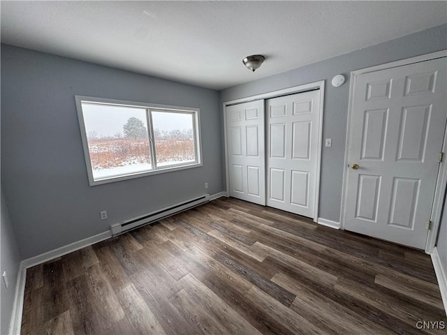 unfurnished bedroom with baseboard heating and dark hardwood / wood-style floors