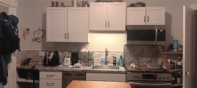 kitchen with stainless steel appliances, decorative backsplash, white cabinets, and sink