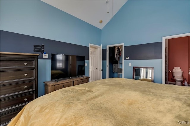 bedroom with a closet, a walk in closet, high vaulted ceiling, and ensuite bath