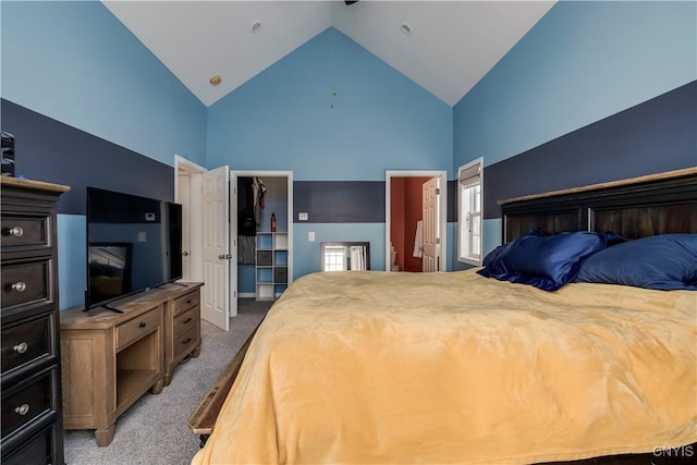 bedroom with high vaulted ceiling, a walk in closet, ensuite bath, and carpet flooring