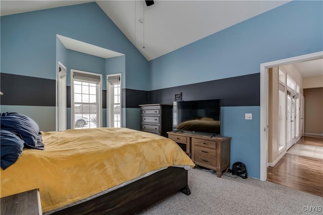 bedroom with light carpet, ceiling fan, and high vaulted ceiling