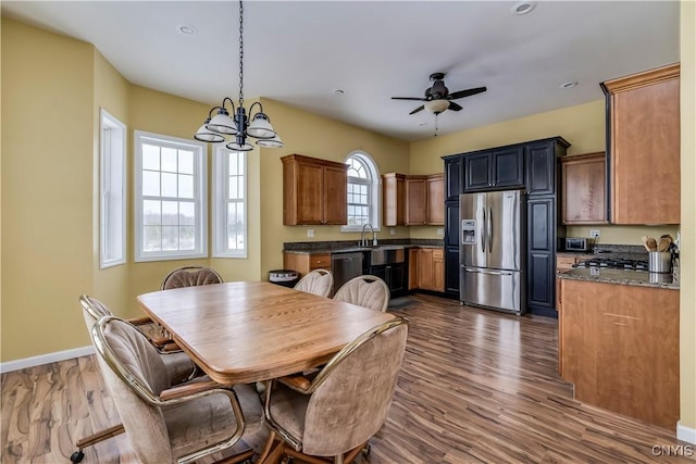 dining space featuring dark hardwood / wood-style flooring, sink, and ceiling fan with notable chandelier