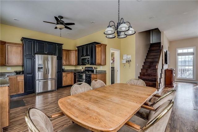 dining area with ceiling fan with notable chandelier and dark hardwood / wood-style floors