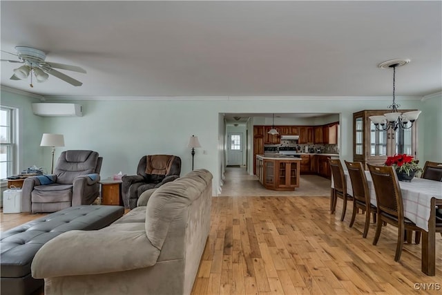 living room featuring ceiling fan with notable chandelier, light hardwood / wood-style flooring, ornamental molding, and a wall mounted air conditioner