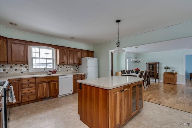 kitchen featuring a kitchen island, tasteful backsplash, decorative light fixtures, white appliances, and a chandelier