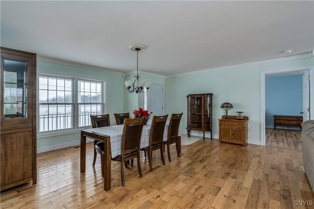 dining area with light wood-type flooring, an inviting chandelier, and ornamental molding