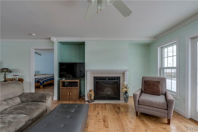 living room with a fireplace, ornamental molding, light hardwood / wood-style floors, and ceiling fan