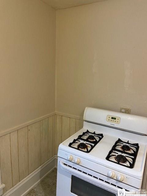 kitchen with wood walls and white range with gas cooktop