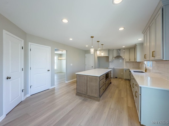 kitchen with decorative backsplash, light wood-type flooring, wall chimney range hood, and a sink