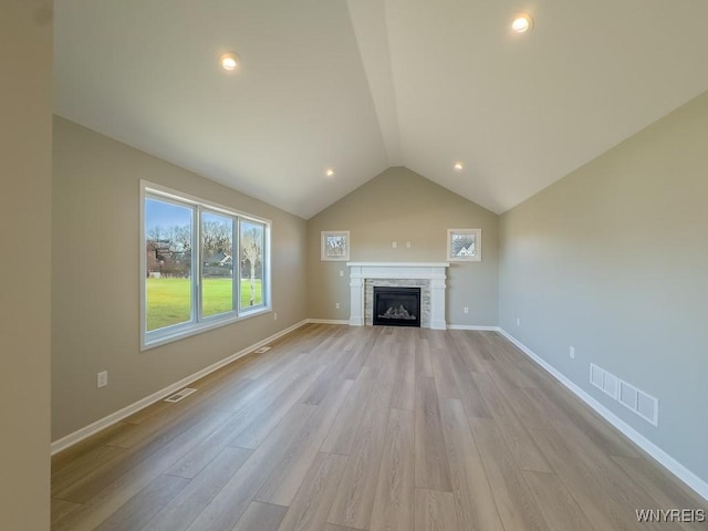 unfurnished living room with visible vents, lofted ceiling, baseboards, and light wood finished floors