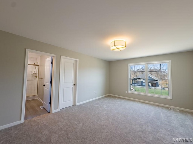 unfurnished bedroom featuring baseboards, carpet floors, and ensuite bathroom