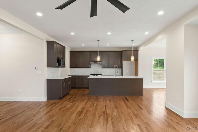 kitchen featuring decorative backsplash, light hardwood / wood-style flooring, pendant lighting, and sink