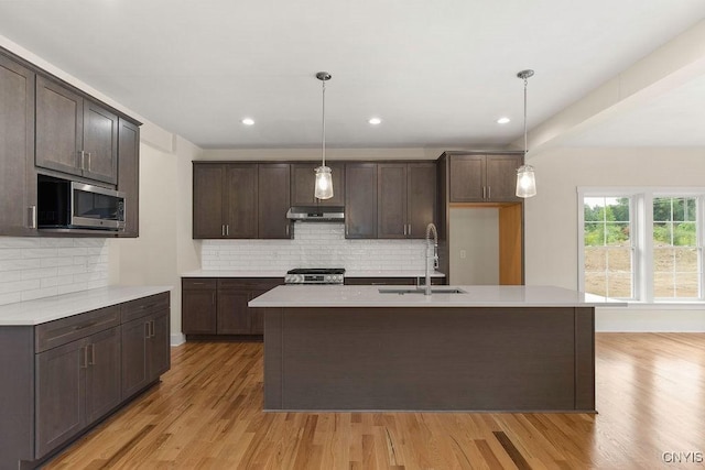 kitchen with stainless steel appliances, an island with sink, hanging light fixtures, and sink