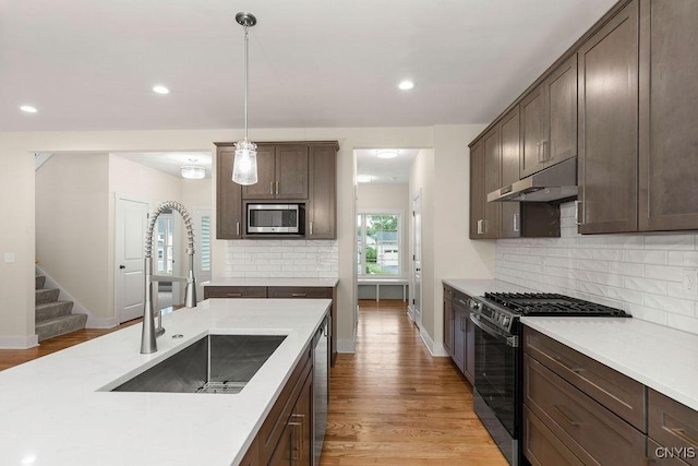 kitchen with sink, hanging light fixtures, backsplash, and stainless steel appliances