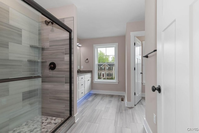 bathroom featuring a shower with shower door and vanity