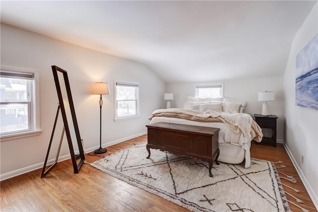 bedroom featuring vaulted ceiling, light hardwood / wood-style flooring, and multiple windows