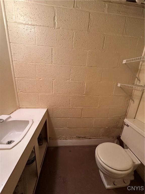 bathroom featuring sink, brick wall, and toilet