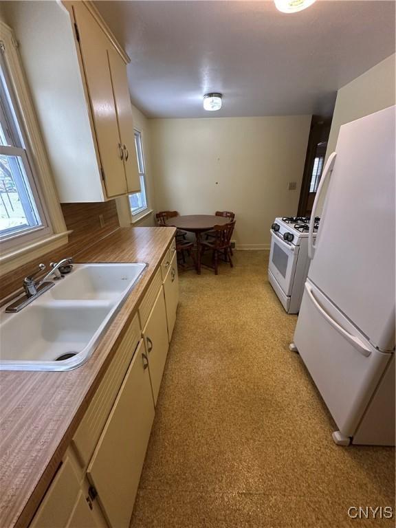 kitchen featuring sink, white appliances, and cream cabinetry