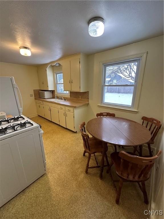 kitchen featuring a textured ceiling, sink, backsplash, and white appliances