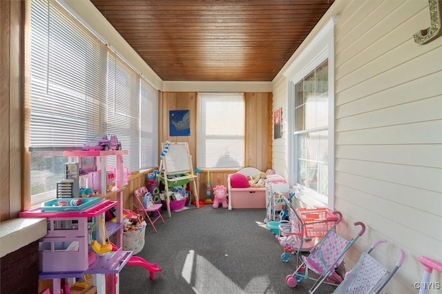 game room featuring carpet flooring, a wealth of natural light, wood walls, and wooden ceiling