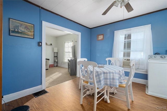 dining space featuring ceiling fan, cooling unit, ornamental molding, light hardwood / wood-style flooring, and washer / clothes dryer