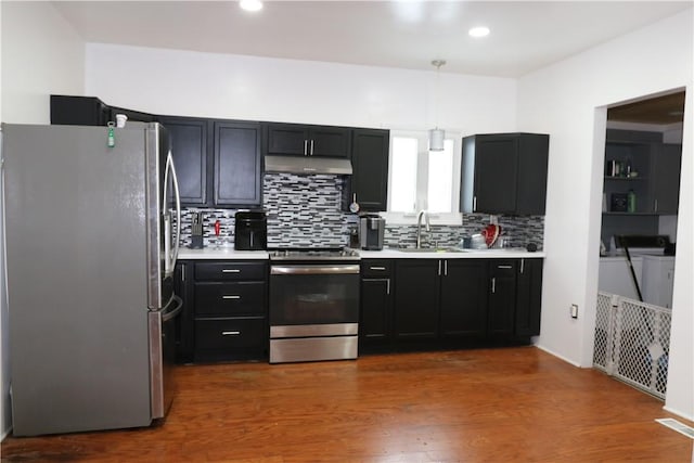 kitchen featuring decorative light fixtures, independent washer and dryer, wood-type flooring, sink, and appliances with stainless steel finishes